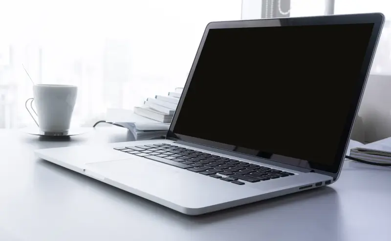 A MacBook with a blank screen sitting on a desk.